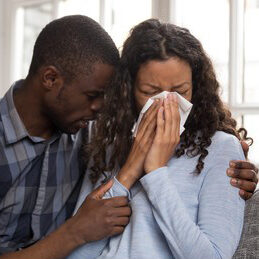 woman cries into tissue as husband comforts